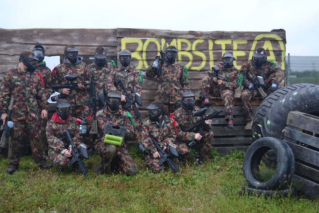 Grupa uczestników paintballa w maskach na polu Tactical Paintball